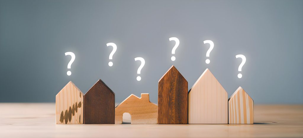 Kleine Modellhäuser mit Fragezeichen, die die Immobiliensuche symbolisieren