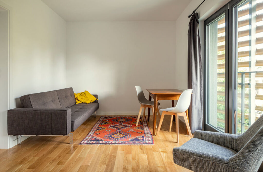 Einblick in ein Mikroapartment mit Sofa, Tisch mit Stühlen und einem Sessel