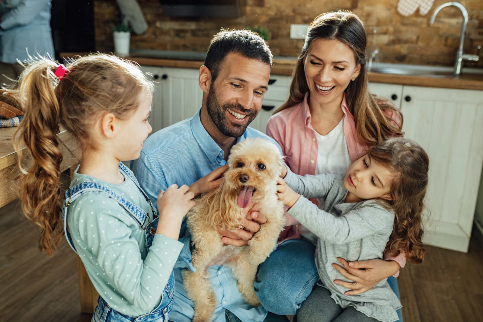 Eine Familie mit zwei Töchtern ist zusammen und kuschelt mit dem Familienhund